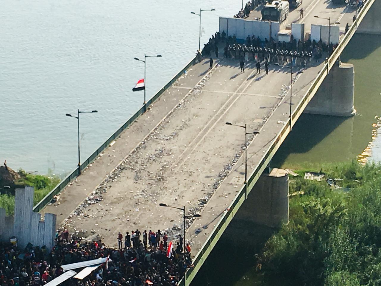 Demonstrators cross the first barrier of Al-Jumhuriya Bridge in Tahrir Square in Baghdad