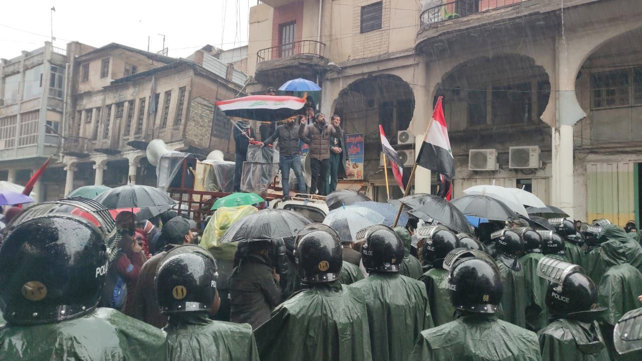 Under pouring rain, demonstrators gather to demand reversing the Iraqi dinar's devaluation