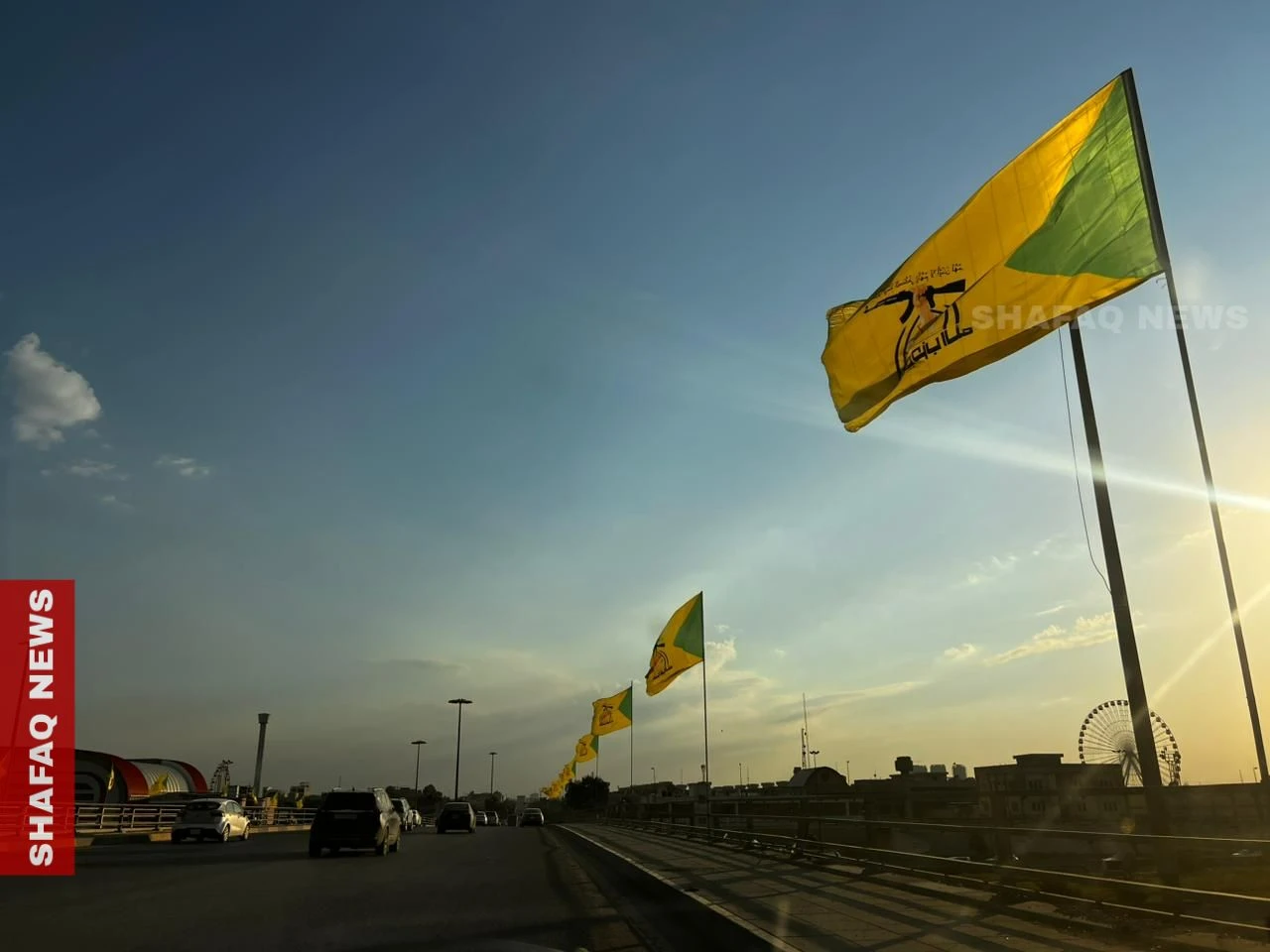 كتائب حزب الله ترفع أعلامها في شوارع وجسور بغداد (صور)
